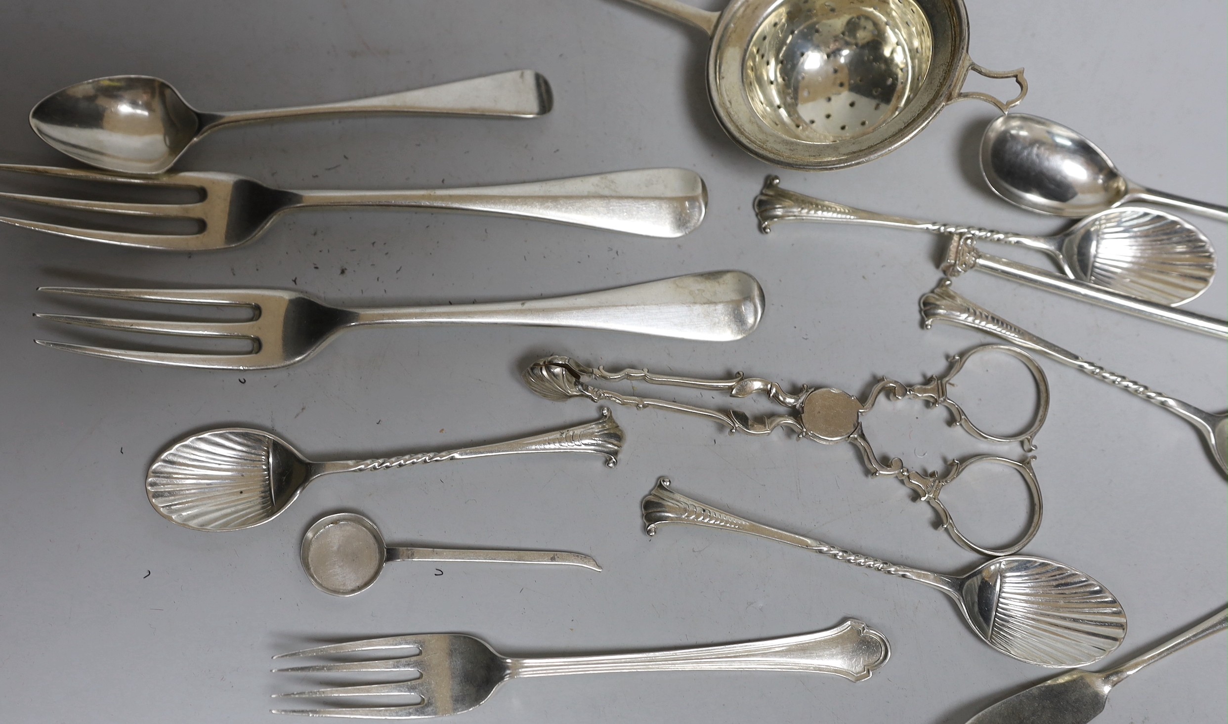 A silver tea strainer and a small collection of assorted 20th century and earlier silver cutlery, various dates and makers, including a pair of mid 18th century sugar nips, 9.7oz.